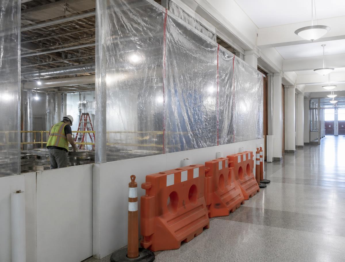 Phased renovation inside an occupied institutional building with hoarding separating the work zone from a public corridor